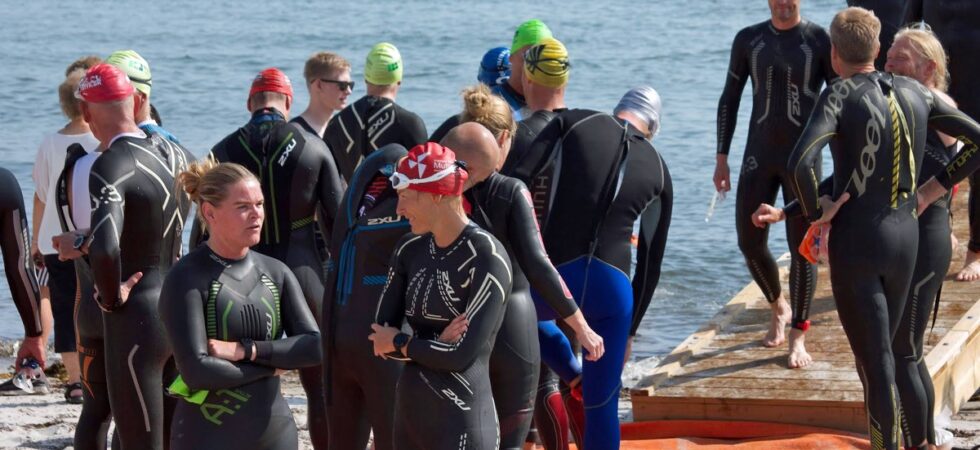 Atleter i våddragt i venteposition på stranden før stævnestart